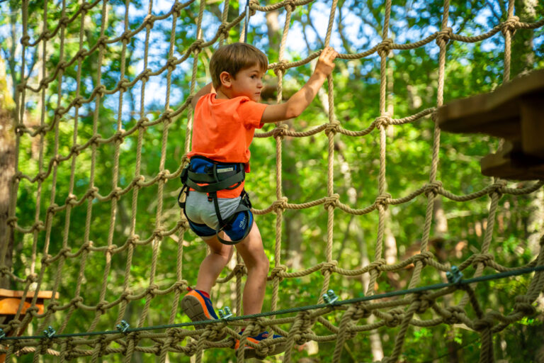 Garçon accroché qui fait de l'accrobranche